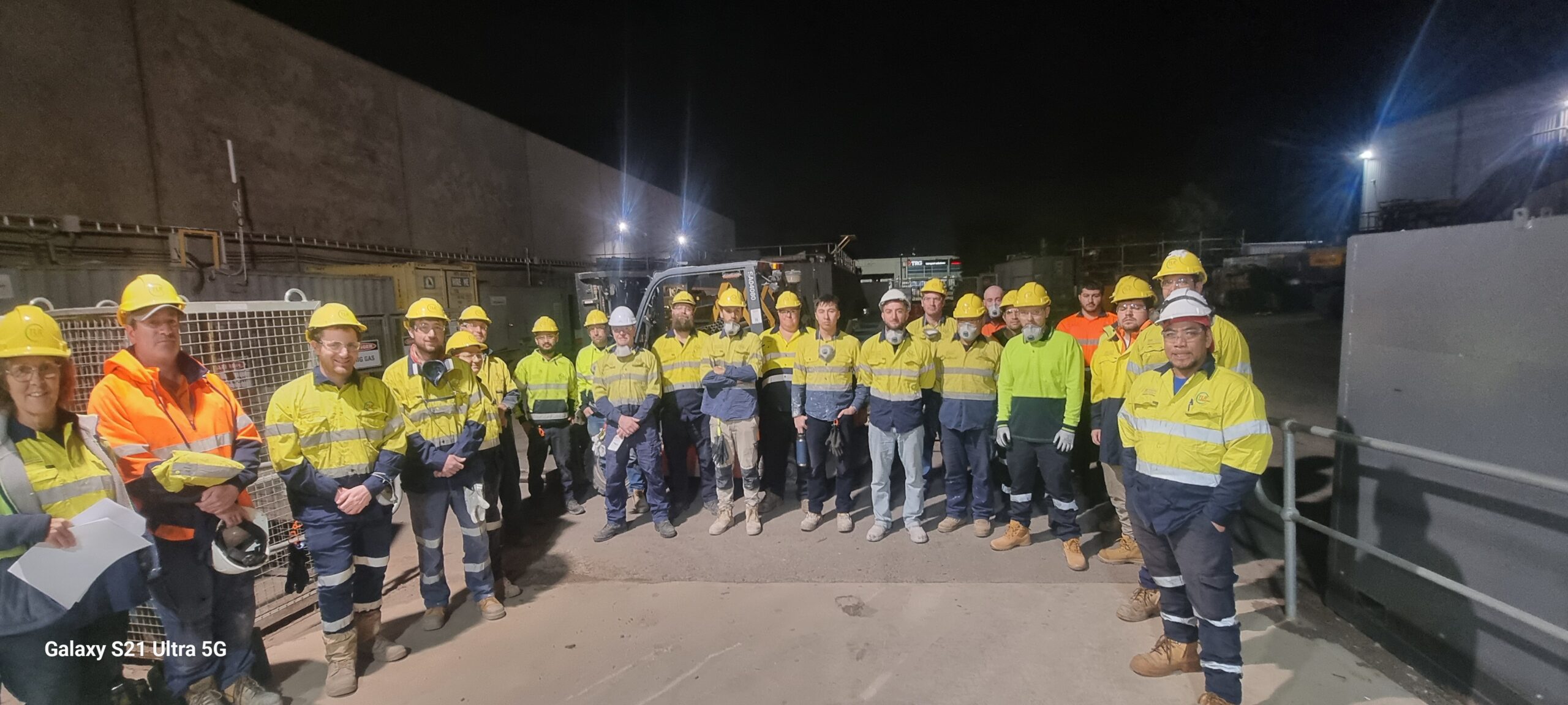 Two industrial workers in hi-vis and hard hats reviewing equipment